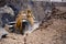 Yellow excavator is filling a dump truck with rocks at coal mines