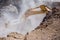 Yellow excavator is filling a dump truck with rocks at coal mines