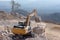 Yellow excavator is filling a dump truck with rocks at coal mines