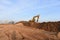 Yellow excavator during groundwork on construction site. Hydraulic backhoe on earthworks. Heavy equipment