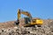 Yellow excavator at landfill for disposal of construction waste. Backhoe dig gravel at mining quarry on blue sky background.