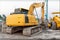 Yellow Excavator Parked at a Construction Site with Dried Muddy Tracks