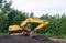 Yellow excavator parked on a pile of crushed stone.