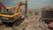 Yellow excavator shovels debris of abandoned building