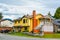 Yellow family house with a car on the driveway on cloudy sky background.