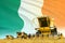 Yellow farm agricultural combine harvester on field with Ireland flag background, food industry concept - industrial 3D