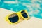 Yellow fashionable plastic sunglasses on the side of the pool