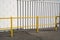 Yellow fences for walkway close to white wall of factory