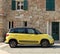 Yellow Fiat 500 L, five door compact minivan, parked on a road side of the old quarter.