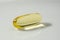 Yellow fish oil capsule pill. Close up fish oil pills on the white plate