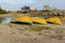 Yellow fishing boats lie on the sand by the river