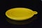 Yellow folding and multifunctional rubber plate, a bowl with a plastic edging on a black glossy surface.