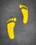 Yellow footprint painted on asphalt road. Walkway lane traffic sign. Foot mark on street texture background. Direction sign.