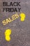 Yellow footsteps on sidewalk towards Black Friday Sales message