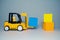 Yellow forklift toy load color cubes. Toys for children. Small forklift loader and three cubes