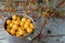 yellow fresh mirabelle plums in a metal pot with sea buckthorn branches and berries on the wooden old blue table