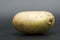 Yellow fresh uncooked potato on black background.