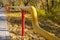 Yellow gas pipe on red poles in autumn park
