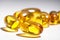 Yellow gel capsules, vitamin E, vitamin D, white background.