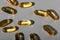 Yellow gelatin capsules on a gray background. Food supplement, vitamin D, omega, vitamin C, multivitamins.