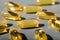 Yellow gelatin capsules on a gray background. Food supplement, vitamin D, omega, vitamin C, multivitamins.