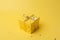 a yellow gift box with golden ribbons on a yellow background. It is an ideal image to illustrate celebration topics, Generative AI