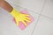 Yellow gloved hand with cleaning rag wiping the floor