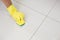 Yellow gloved hand with sponge cleaning the floor
