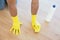Yellow gloved hands with sponge cleaning the floor