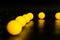 Yellow glowing garland neatly straight-lined balls on a black background with light reflection