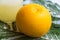 yellow grapefruit next to a glass with its juice, leaf on top of the table