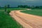 Yellow gravel road winding in a green field