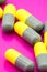 Yellow and gray capsule medicines on pink