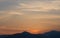 Yellow-gray sunset sky with light clouds over the mountains and the sea