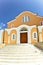 The yellow greek church with white windows and stairs .