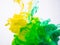 Yellow and green paint make an abstract acrylic cloud in liquid. Two ink colours photographed while transforming into