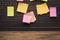 Yellow, green, pink reminder notes on a wooden board, empty space for text