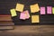 Yellow, green, pink reminder notes on a wooden board, empty space for text