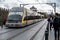 Yellow and grey train chugging down a set of train tracks in a bustling urban cityscape