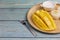 Yellow half  mango with small fork. Mango fruit cubes on the Blue wooden table. Tropical fruit asia. Fresh yellow mango peel and