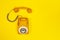 Yellow handset of a telephone on a yellow background.