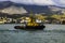 Yellow harbor tug close-up against the backdrop of the seaport and mountains.