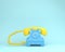 Yellow headphone against blue retro telephone on light blue colo