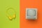 Yellow headphones and a gray monitor on a green and orange background. Flat lay