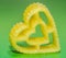Yellow heart shape pasta, green background, close up