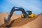 Yellow heavy excavator and bulldozer excavating sand and working during road works, unloading sand and road metal