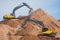 Yellow heavy excavator and bulldozer excavating sand and working during road works, unloading sand and road metal during construct