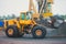 Yellow heavy excavator and bulldozer excavating sand and working during road works, unloading sand and road metal during construct