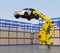 Yellow heavyweight robotic arm carrying white SUV in the assembly factory