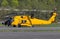 Yellow helicopter sitting on tarmac with crew